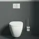 Weißes Wand-WC neben einer Toilettenbürstengarnitur mit Glasbehälter und Chromgriff. Ideal Standard ist auf der Betätigungsplatte sichtbar.